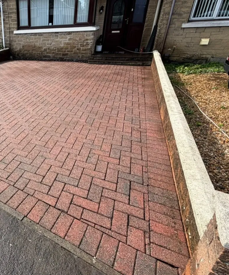 The same herringbone driveway after cleaning, bright red paving restored